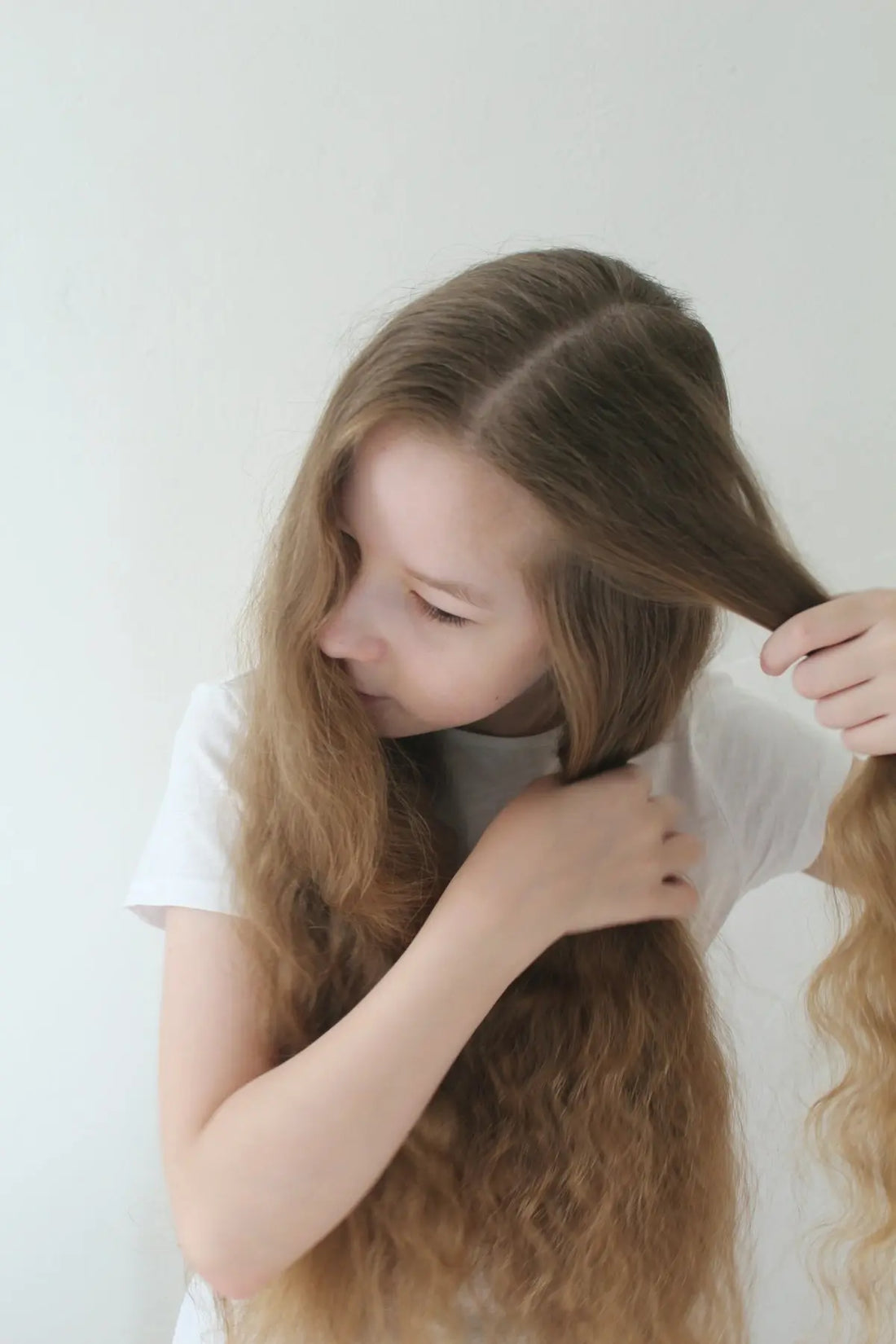Young girl braiding her long brown hair