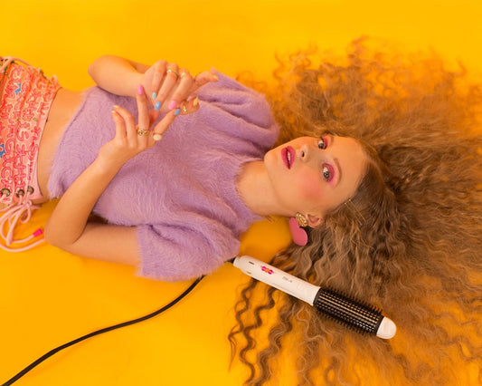 Young woman with voluminous curly hair and styling tool.